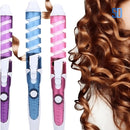 Modelador de cachos elétrico com cores rosa, azul e roxo e cabelo cacheado castanho