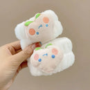 Mãos segurando dois scrunchies peludos brancos com detalhes bordados em formato de rostos coloridos