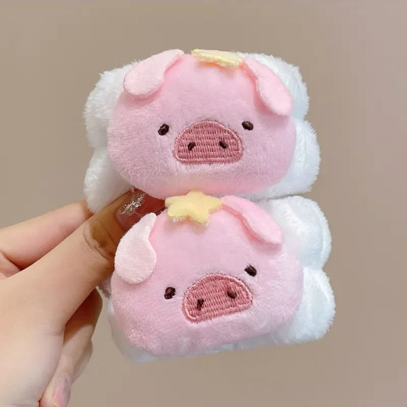 Mãos segurando pelúcia rosa de porquinho com estrela amarela, fundo bege