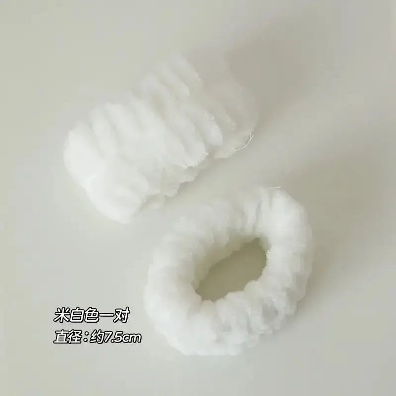 Dois elásticos de cabelo felpudos brancos sobre fundo claro, textura macia, diâmetro cerca de 7,5 cm