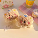 Meias felpudas ursinho bege com detalhes coloridos ao lado de bebida de limão e pote de sobremesa