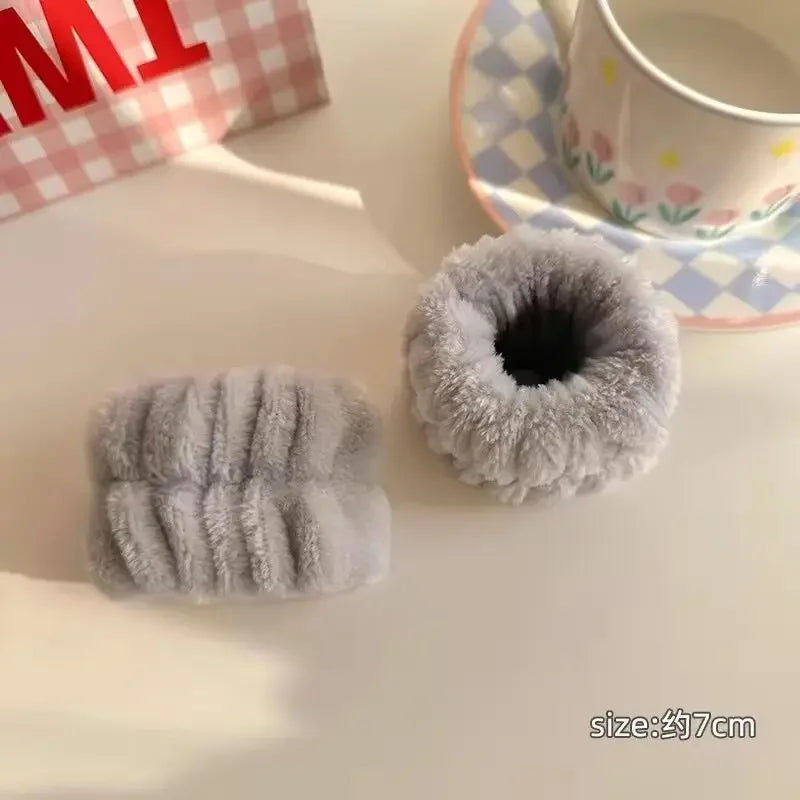 Elásticos de cabelo cinza felpudo macio ao lado de xícara com pires decorado