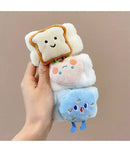 Mão segurando três pulseiras pelúcia branca com decoração de fatia de pão, morango e nuvem azul sorridentes