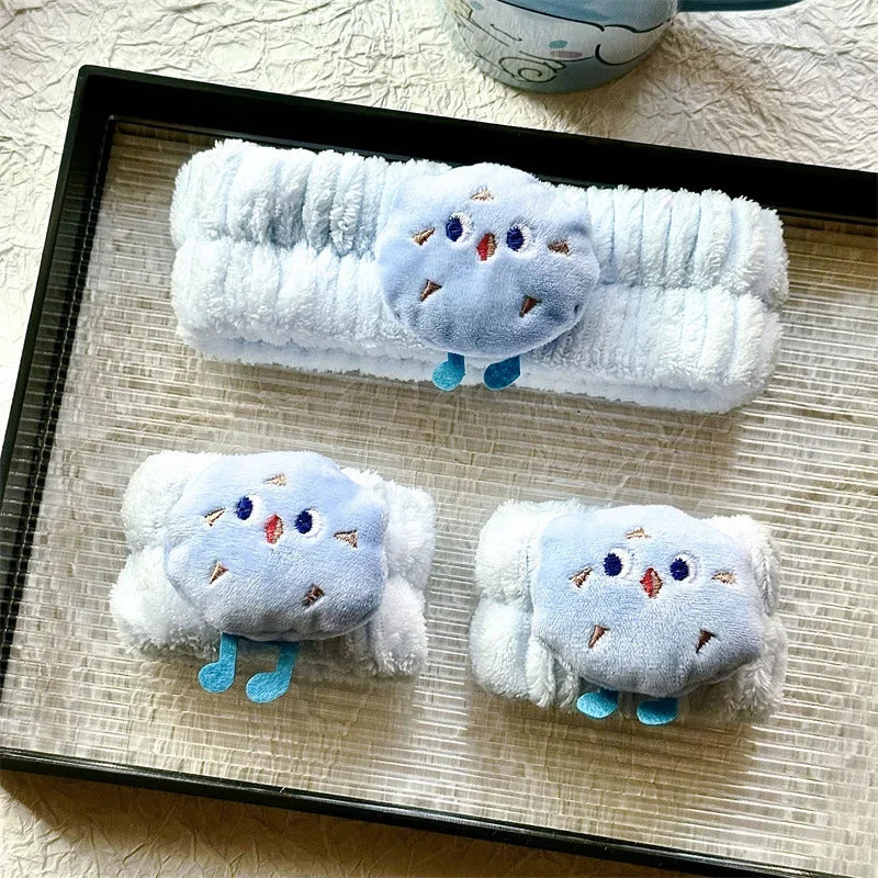 Faixa e polainas felpudas brancas com detalhe azul decorativo, exibidas em bandeja preta sobre superfície texturizada