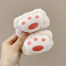 Mãos segurando faixas de cabelo felpudas rosa claro com design de patinha rosa