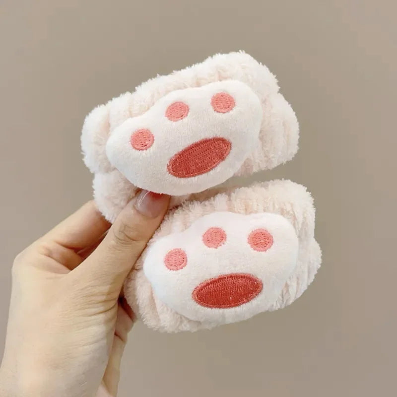 Mãos segurando faixas de cabelo felpudas rosa claro com design de patinha rosa